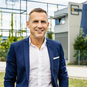 Mann in Anzug lächelt vor Cteam Gebäude, symbolisiert Expertise in Consulting und Anlagenbau. Mann in Anzug lächelt vor Cteam Gebäude, symbolisiert Expertise in Consulting und Anlagenbau.