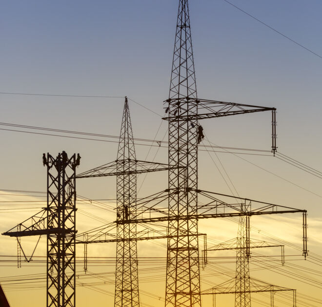 Stromleitungen und Freileitungsmasten im Sonnenuntergang mit Monteuren bei Arbeiten an der Leitung. Stromleitungen und Freileitungsmasten im Sonnenuntergang mit Monteuren bei Arbeiten an der Leitung.