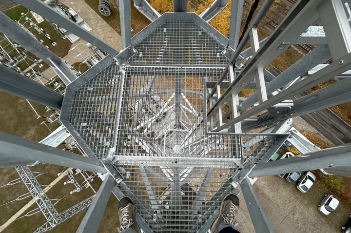 Arbeit auf Höhe: Blick von einem Cteam-Gitterrost-Podest auf Stromleitungs-Infrastruktur. Arbeit auf Höhe: Blick von einem Cteam-Gitterrost-Podest auf Stromleitungs-Infrastruktur.